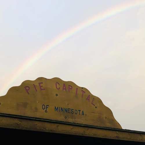 Sign reading "Pie Capital of Minnesota" with a rainbow in the background.