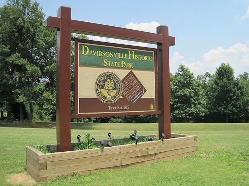 Sign for Davidsonville Historic State Park, featuring the park's name and established date, surrounded by greenery.