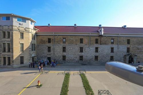 A historic stone building with a red roof, people gathered outside, and a clear blue sky above.