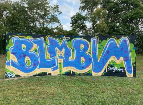 Colorful graffiti on a wall featuring the word "BLMBM" in bold blue letters with green accents.