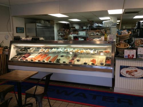 Display case filled with various seafood options, including fish and shellfish, in a casual seafood market setting.