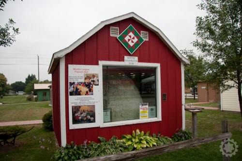 Red barn-shaped building displaying a sign for the "World's Largest Popcorn Ball" with informational posters.