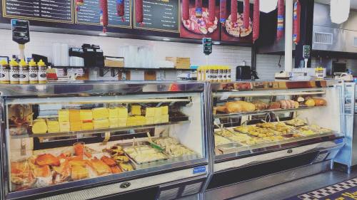 A deli display case filled with various meats, cheeses, and prepared foods, with condiments on the counter above.