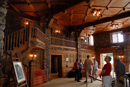 A spacious, rustic interior with stone walls and wooden beams, featuring visitors exploring the room.