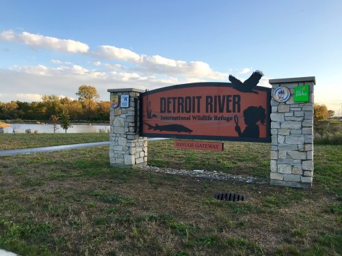Sign for Detroit River International Wildlife Refuge, featuring a silhouette of a bird and scenic background.
