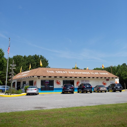A seafood restaurant named "The Great Yachting Clam Shack" with a parking lot and flags on the roof.