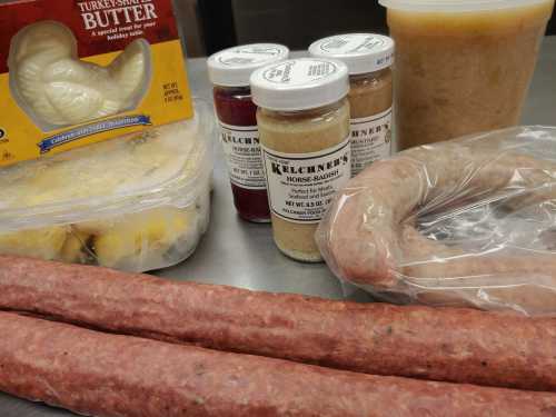 A variety of food items including turkey butter, sausages, jars of condiments, and a container of applesauce.