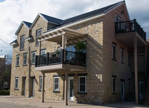 A two-story stone building with a balcony, featuring a modern design and large windows.