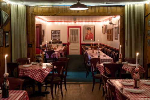 Cozy restaurant interior with checkered tablecloths, candlelit tables, and vintage decor, creating a warm atmosphere.