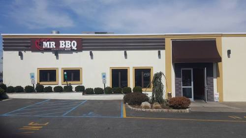 Exterior of Mr. BBQ restaurant featuring a sign, large windows, and a parking lot with accessible spaces.