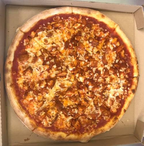 A large pizza topped with cheese, chicken pieces, and a rich tomato sauce, in a cardboard box.