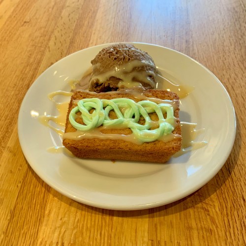 A slice of cake with green frosting and a scoop of chocolate ice cream drizzled with caramel on a white plate.
