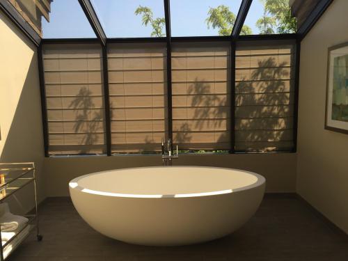 A modern bathroom featuring a freestanding oval bathtub and large windows with natural light and shadows.