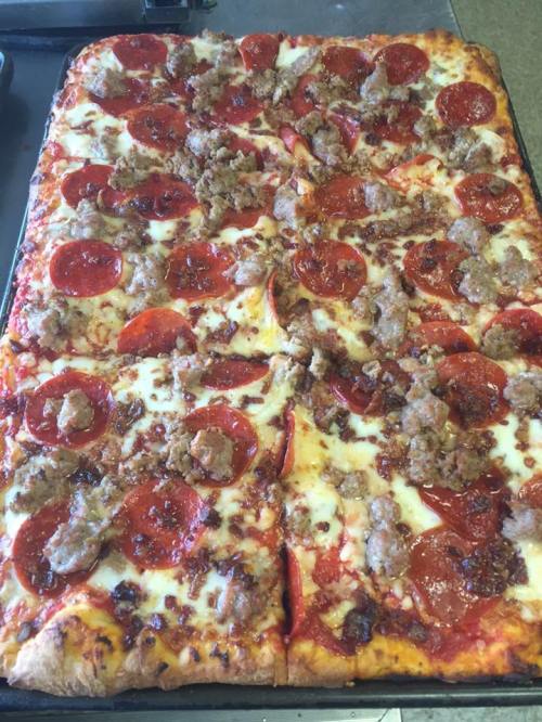 A rectangular pizza topped with pepperoni and sausage on a golden crust, with melted cheese and crispy edges.