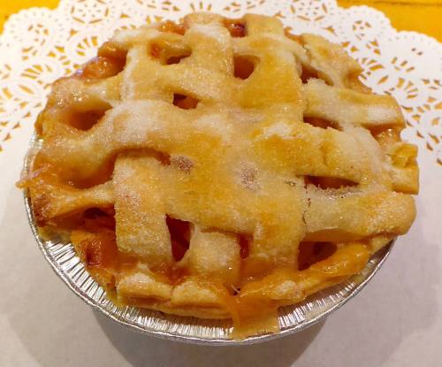 A golden-brown fruit pie with a lattice crust, sitting on a decorative white doily.