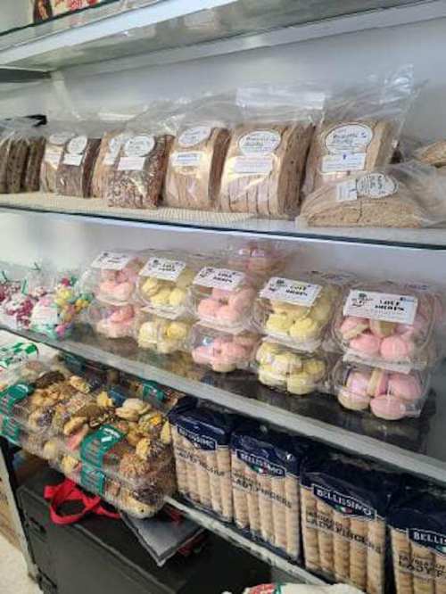 A display of assorted baked goods, including cookies, colorful macarons, and packaged treats on shelves.