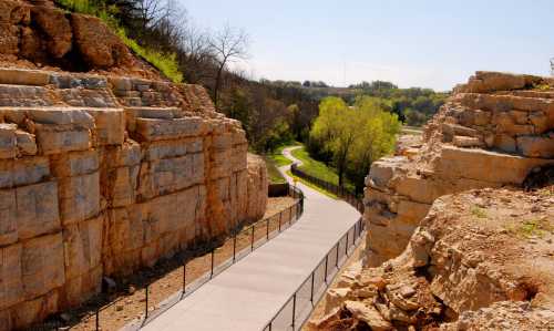 A winding path surrounded by rocky cliffs and greenery under a clear blue sky.