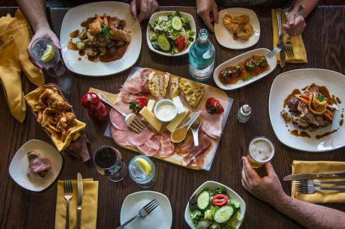 A table spread with various dishes, including salads, meats, and appetizers, surrounded by drinks and utensils.