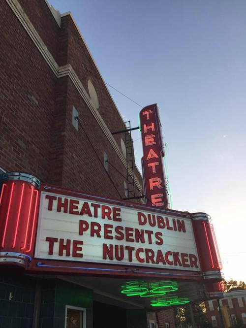 Neon marquee of Theatre Dublin announcing a performance of "The Nutcracker" against a sunset sky.