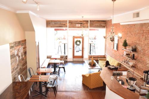 Cozy café interior with wooden tables, a yellow couch, and a welcoming entrance decorated for the holidays.
