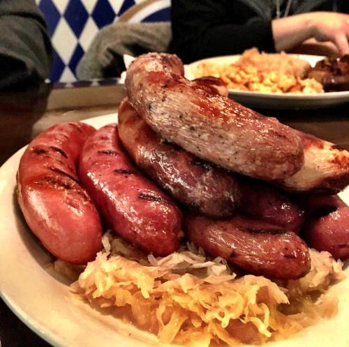 A plate of assorted grilled sausages stacked on a bed of sauerkraut.
