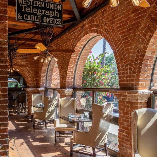 Interior of a cafe with arched brick walls, elegant chairs, and a sign for Western Union Telegraph & Cable Office.