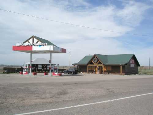 A gas station and trading post with a wooden building, set against a cloudy sky in a rural area.