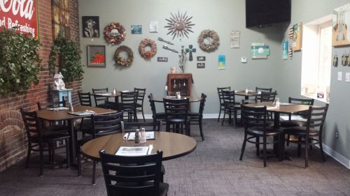 Cozy restaurant interior with wooden tables, chairs, and decorative wall art in a warm, inviting atmosphere.