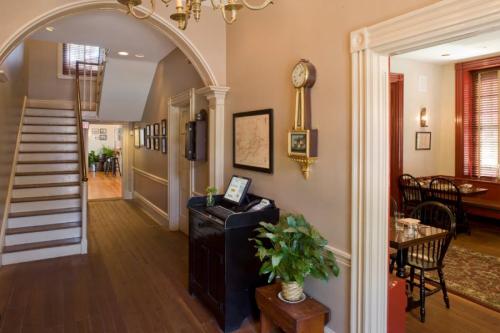 A cozy hallway with a staircase, vintage decor, and a glimpse of a dining area in a warm-toned interior.