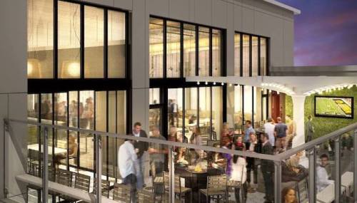 A modern restaurant with large windows, outdoor seating, and a lively crowd enjoying food and drinks.