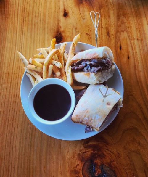 A plate with two sandwiches and a side of fries, accompanied by a small bowl of dipping sauce.