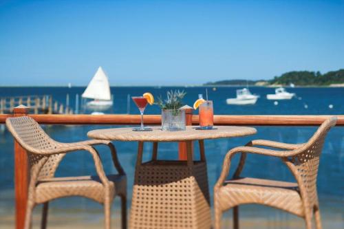 A seaside table with two cocktails, overlooking boats on the water and a clear blue sky.