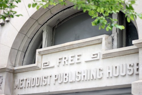 Sign on a building reading "Free Methodist Publishing House," framed by green leaves.