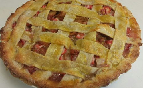 A freshly baked strawberry pie with a golden lattice crust, showcasing vibrant red filling peeking through.