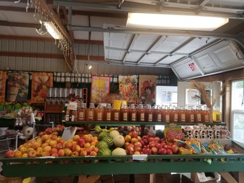 A vibrant market display with various apples, jars, and colorful decorations in a rustic setting.
