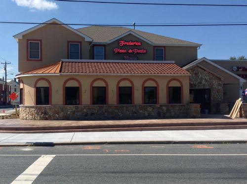 Exterior of Frederico's Pizza & Pasta, featuring a stone facade and arched windows, on a sunny day.