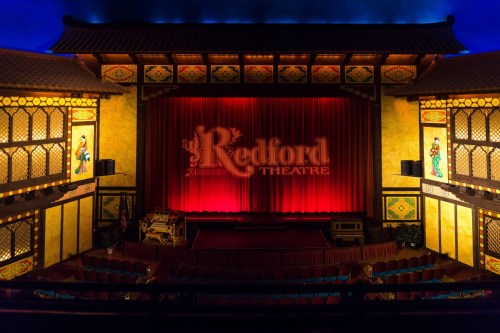 Interior of the Redford Theatre, featuring a red curtain and ornate Asian-inspired decor.