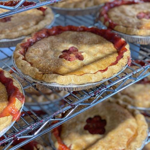 A close-up of freshly baked fruit pies cooling on a wire rack, showcasing golden crusts and vibrant fillings.