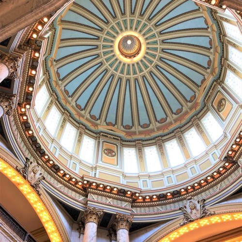A beautifully designed dome ceiling with intricate patterns and a central light fixture, viewed from below.
