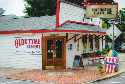 A quaint grocery store with a sign reading "Every cloud has a silver lining" and colorful beach-themed decor.