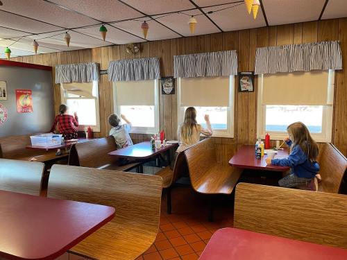 A cozy diner interior with children sitting at booths, looking out the windows, and enjoying their meals.