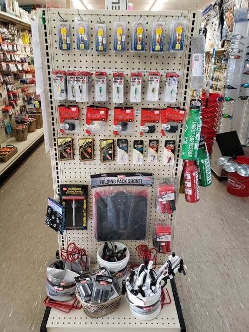 Display of various tools and accessories, including shovels, fishing gear, and other hardware items on a pegboard.