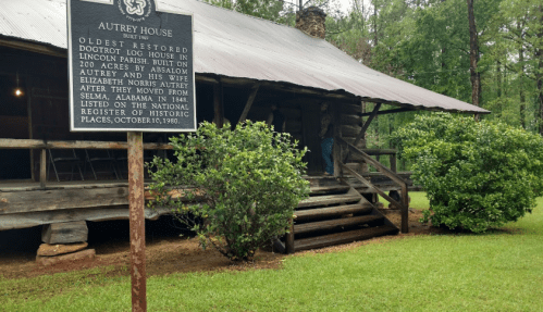 Sign for Autrey House, the oldest restored dogtrot log house in Lincoln Parish, surrounded by greenery.