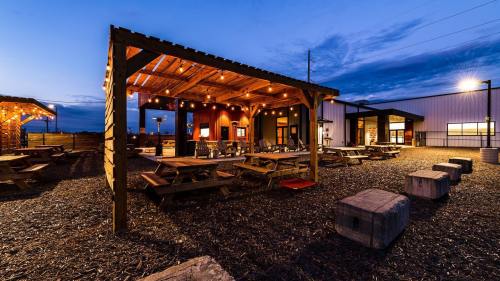 Outdoor dining area with wooden picnic tables, string lights, and a cozy atmosphere at dusk.