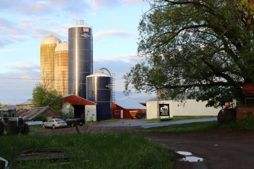A rural farm scene featuring silos, a red barn, and a grassy area under a partly cloudy sky.