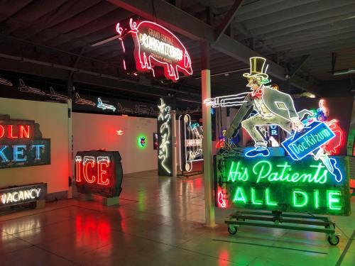 A vibrant display of neon signs, including a doctor figure and various colorful advertisements in a dimly lit space.