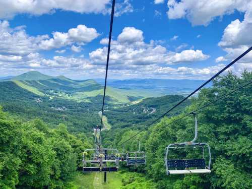 A scenic view from a chairlift, overlooking lush green mountains and a blue sky with fluffy clouds.