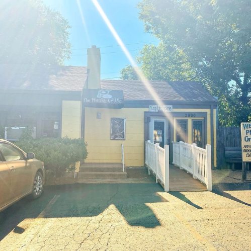 Exterior view of a restaurant called "The Hungry Griddle," with a sunny atmosphere and a nearby parking area.