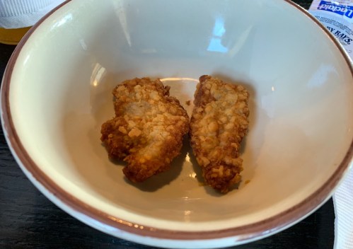 Two crispy fried chicken pieces in a small bowl.