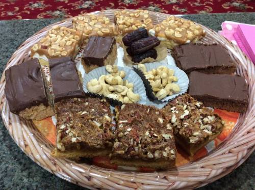 A woven basket filled with assorted desserts, including chocolate bars, nut treats, and date squares.